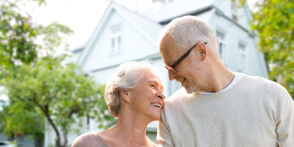 family, age, home, real estate and people concept - happy senior couple hugging over living house background